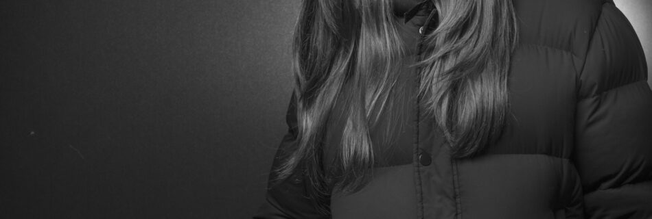 A black-and-white depiction of a woman posing in a black jacket.